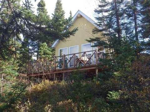Le chalet du Huard est entouré d'arbres et possède une galerie donnant sur la nature.