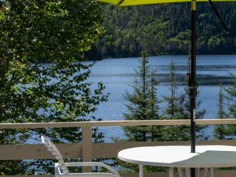 Une table et des chaises sont installées sur la galerie du chalet avec une vue sur le lac.