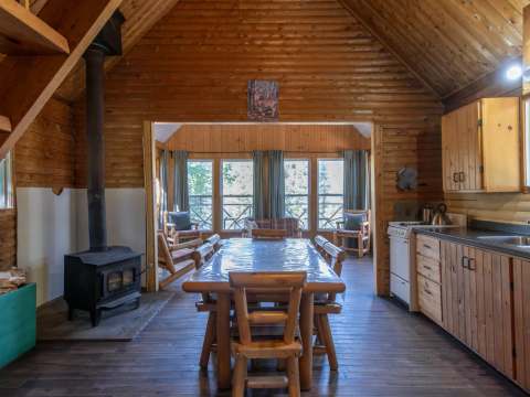 L'aire ouverte du chalet comprend une salle à manger et une cuisine avec poêle à bois.