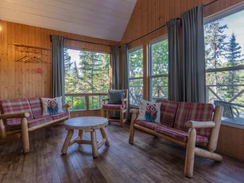 Le salon du chalet offre une vue lumineuse sur la forêt environnante.