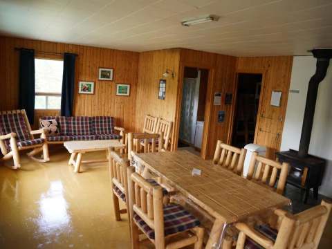 L'aire ouverte du Chalet du Bûcheron comprend un salon et une table à manger avec un poêle à bois.