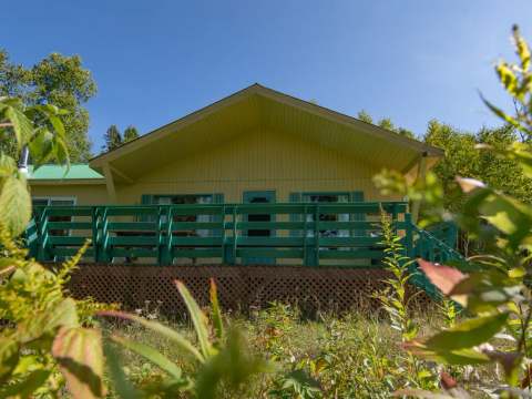 Vue du chalet du Trappeur avec sa galerie en bois sous un ciel bleu.