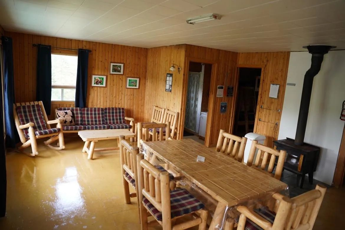 L'aire ouverte du Chalet du Bûcheron comprend un salon et une table à manger avec un poêle à bois.