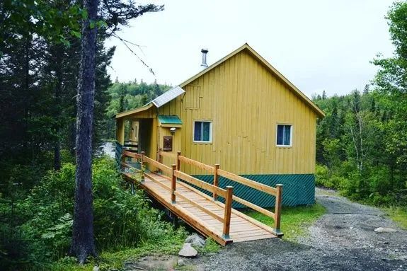 Le chalet du Bûcheron offre un accès extérieur avec une rampe en bois menant à la galerie.