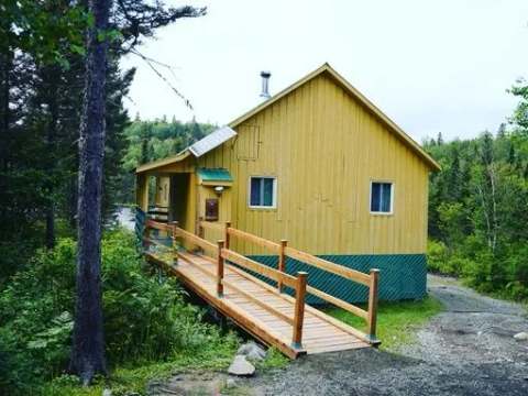 Le chalet du Bûcheron offre un accès extérieur avec une rampe en bois menant à la galerie.