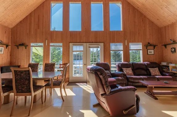 L'aire ouverte du chalet dispose d'une salle à manger et d'un salon avec une grande fenestration.