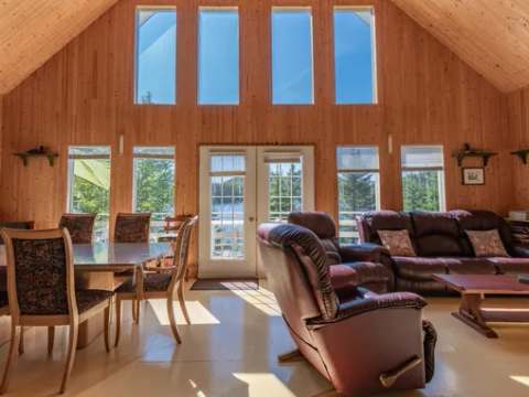 L'aire ouverte du chalet dispose d'une salle à manger et d'un salon avec une grande fenestration.