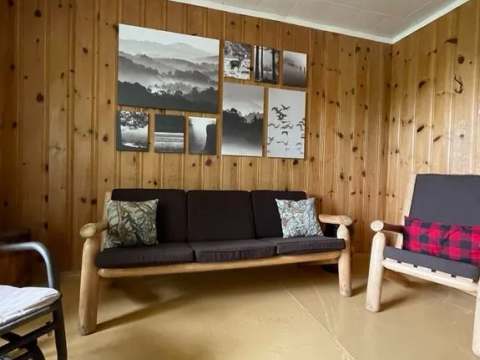 Le salon du chalet est aménagé avec un canapé et des fauteuils en bois dans une ambiance rustique.