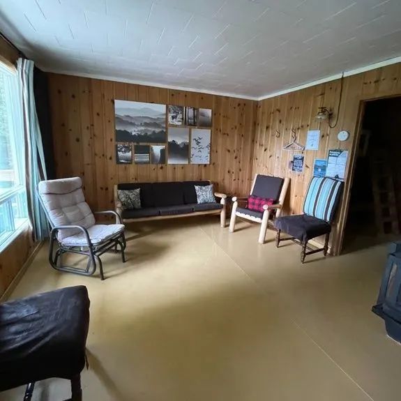 Le salon du chalet du Huard propose un espace de détente avec mobilier en bois et vue sur l'extérieur.