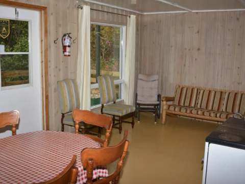 L'intérieur du chalet comprend une table à manger, des chaises et un coin salon avec canapé.