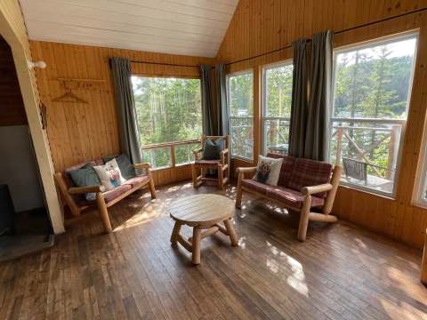 Le salon du Chalet de l'Ours offre une aire de détente lumineuse avec vue sur la nature.