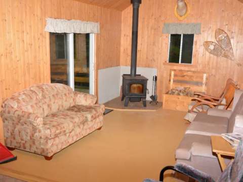 Le salon du chalet est aménagé avec deux canapés, un poêle à bois et une décoration rustique.