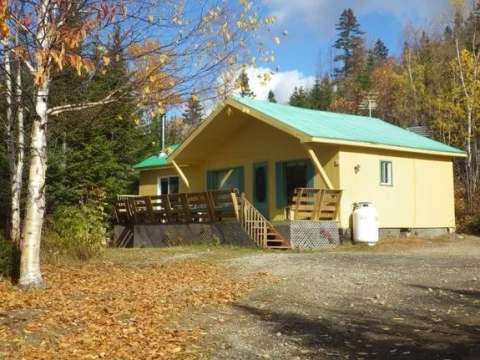 Le chalet du Huard est entouré d'arbres et dispose d'une grande terrasse en bois.