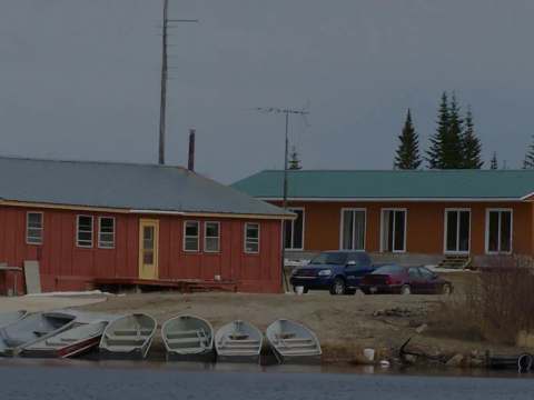 Overview of the cabins located by the water with boats on the shore.