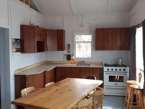 Functional kitchen area with wooden table and stove in cabin 10.