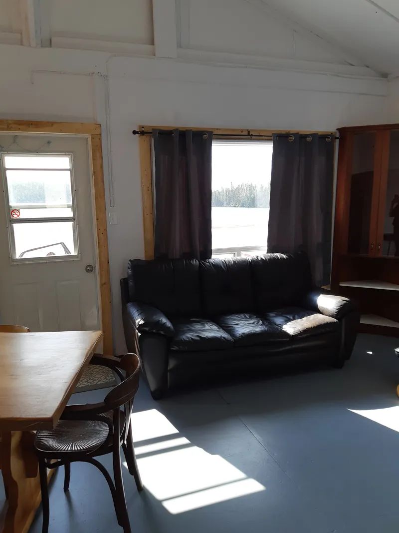 The bright living area of the cabin features a comfortable sofa and a wooden dining table.