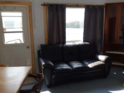 The bright living area of the cabin features a comfortable sofa and a wooden dining table.