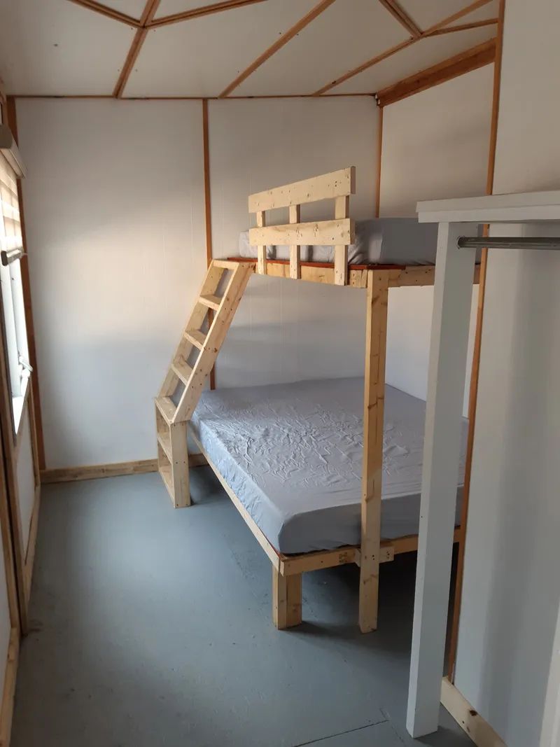 This cottage bedroom features a bunk bed with a large single bed on the bottom level.