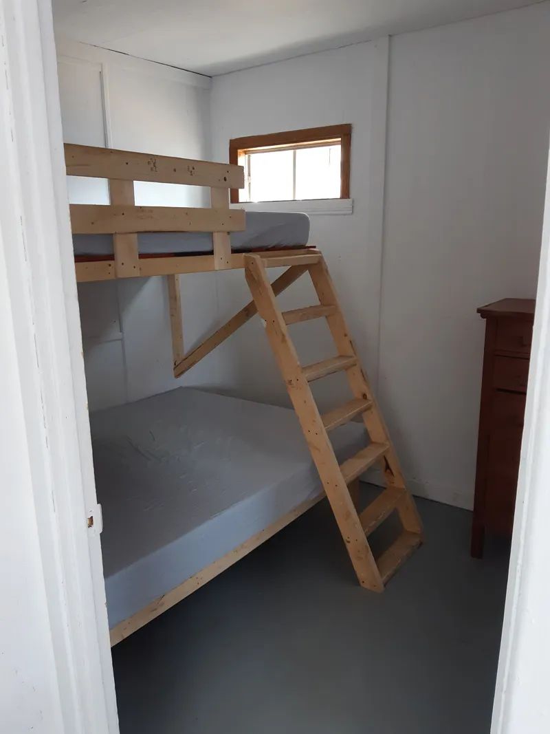 This bedroom in cabin 10 features a wooden bunk bed and a dresser.