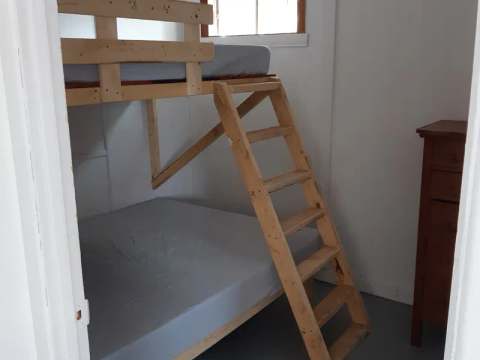 This bedroom in cabin 10 features a wooden bunk bed and a dresser.