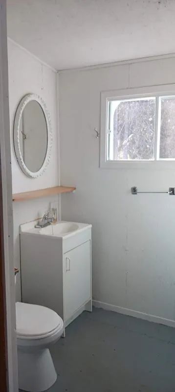 Vue de la salle de bain fonctionnelle avec lavabo et miroir dans le chalet.