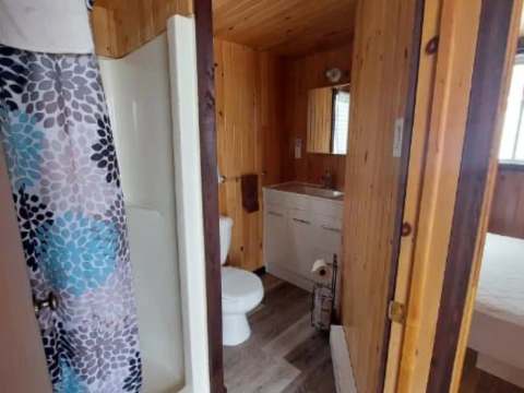 Cette salle de bain fonctionnelle est équipée d'une douche et d'un lavabo au revêtement en bois.