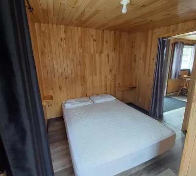 Cette chambre comporte un lit double avec des murs et un plafond lambrissés en bois naturel.
