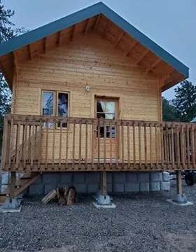Vue de face d'un chalet en bois avec galerie surélevée.