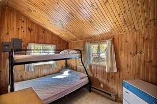 Cette chambre de chalet comporte un lit superposé avec finition en bois naturel.