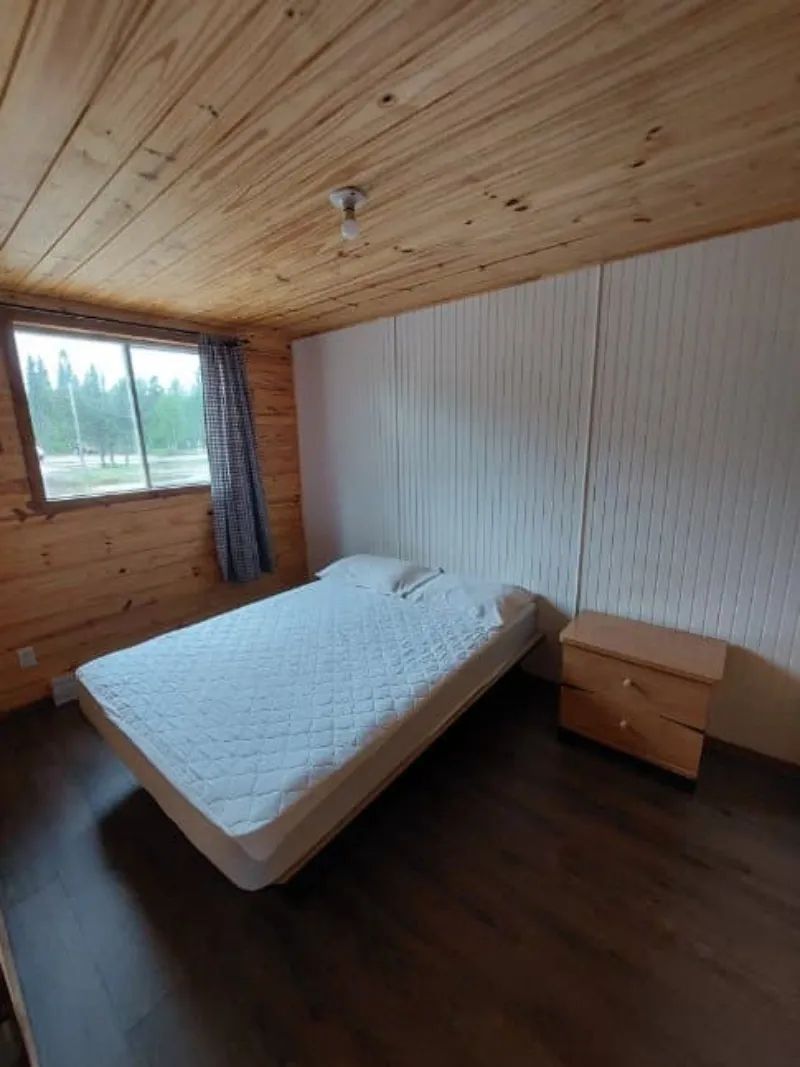 Cette chambre dispose d'un lit double avec une table de chevet et une fenêtre donnant sur l'extérieur.
