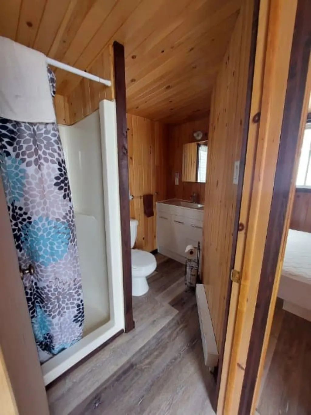 Cette salle de bain fonctionnelle est équipée d'une douche et d'un lavabo au revêtement en bois.