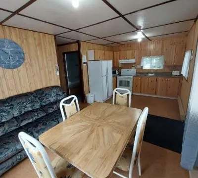 This bathroom features wood paneling on the walls and an adjoining shower.