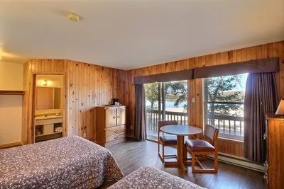 This standard room includes two beds, a table, and a view of the lake.