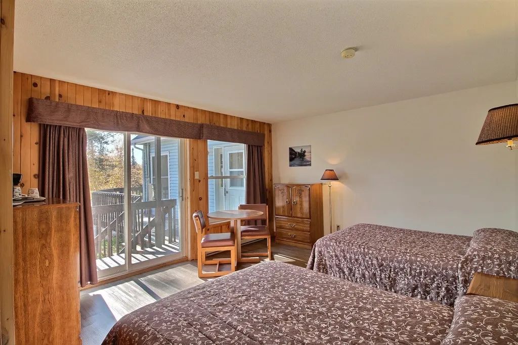This standard room features two beds, a small table with two chairs, and access to the patio.