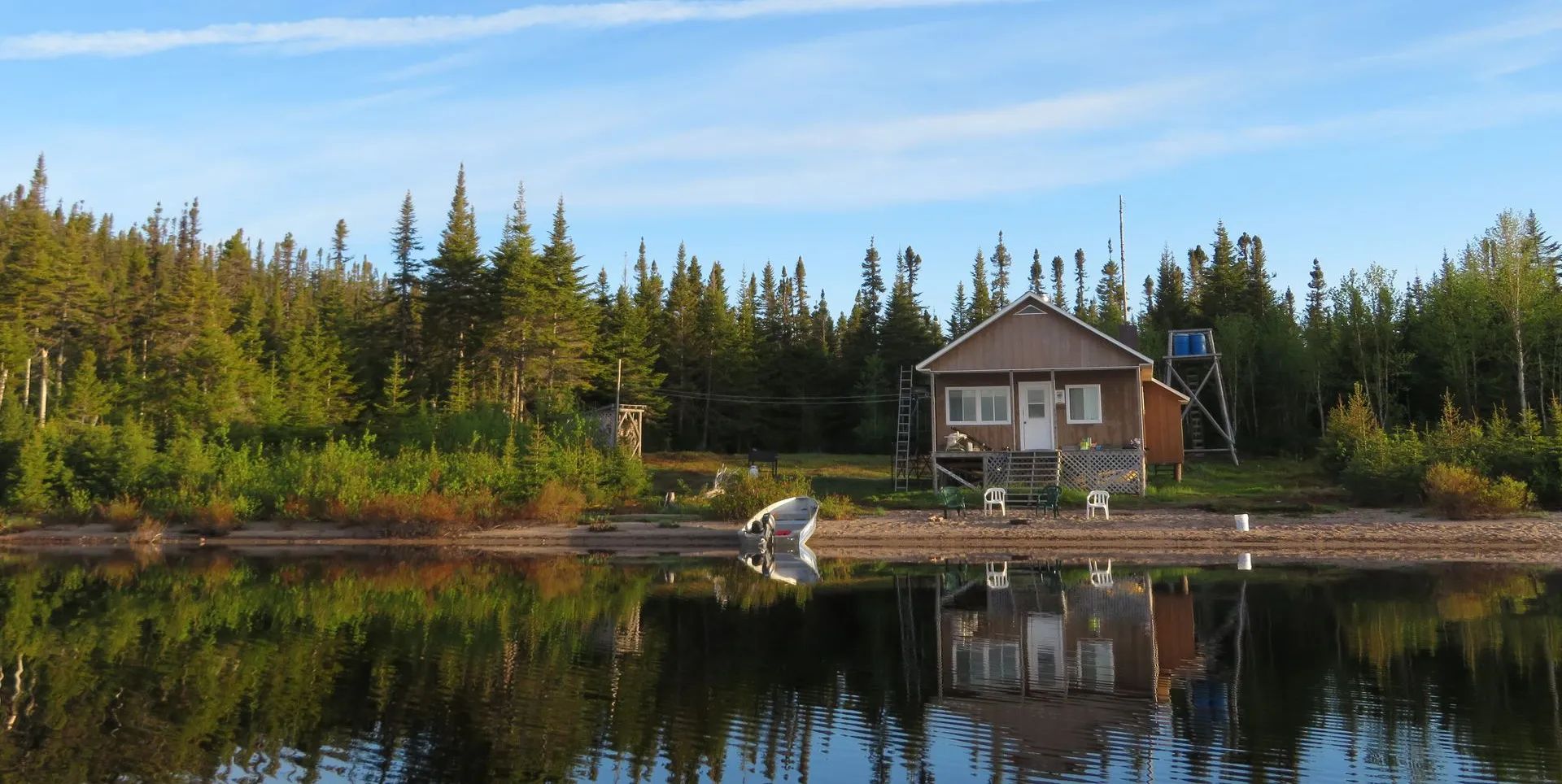 Vue du chalet Pimbina situé au bord de l'eau avec une petite embarcation sur le rivage.