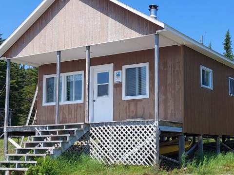 The Pimbina cabin features a covered porch and outdoor wooden stairs.