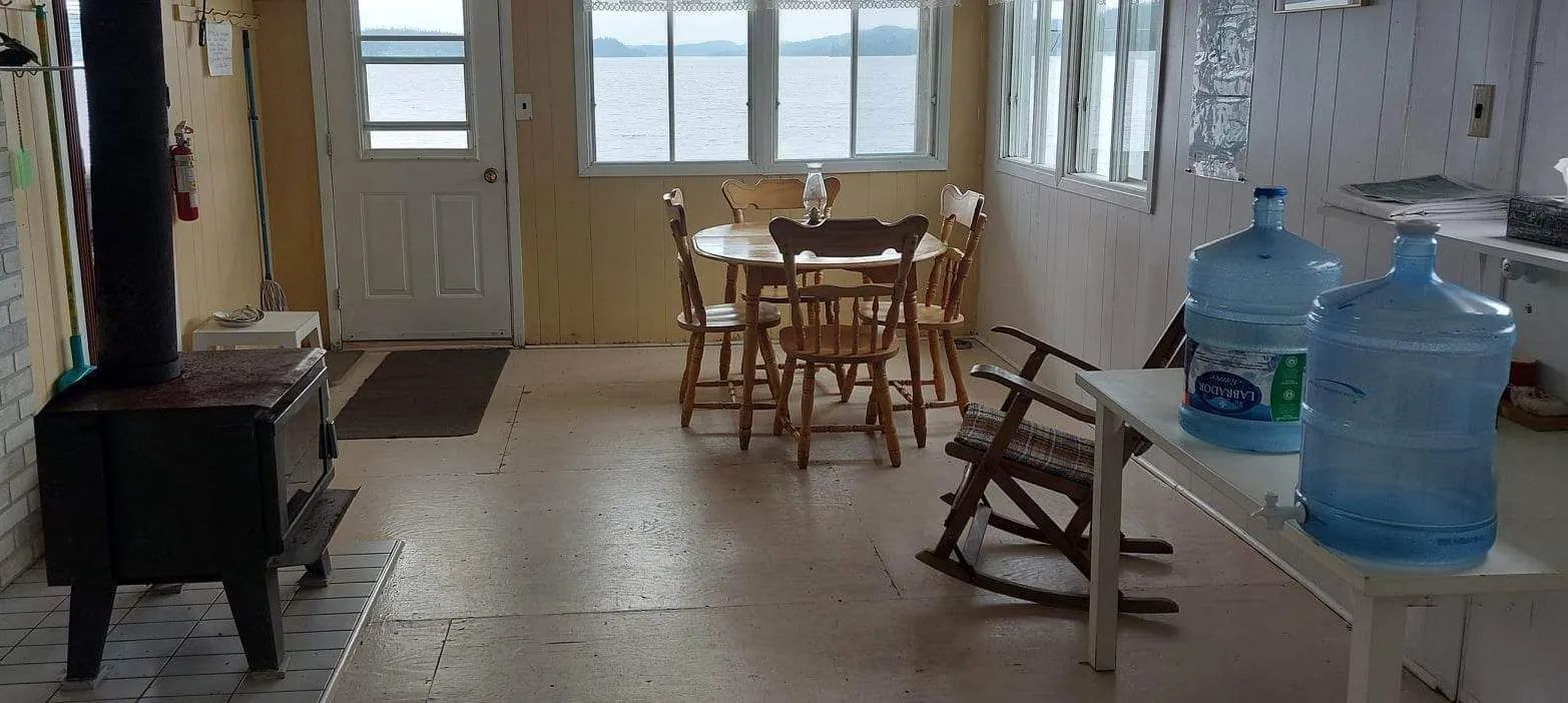 View of the Pimbina cabin's living area including a dining table and a wood stove.