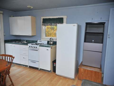 La cuisine fonctionnelle du chalet comprend une cuisinière, un réfrigérateur et un espace repas.
