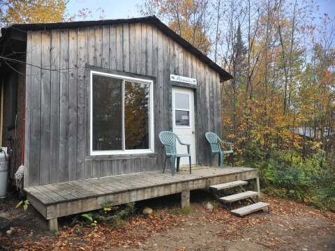 Exterior view of Le Pionnier cabin with its wooden deck and outdoor chairs.