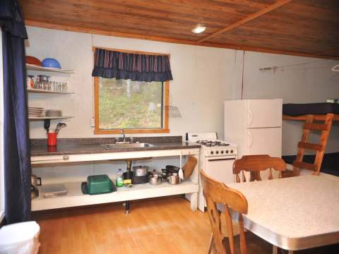 The equipped kitchen of Le Pionnier cabin with its dining area and bunk beds.