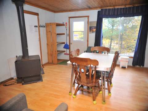 The cottage dining area features a table with chairs and a wood stove.