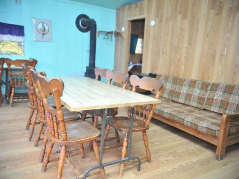 The dining area of the Le Vétéran cabin includes a wooden table and a heating stove.