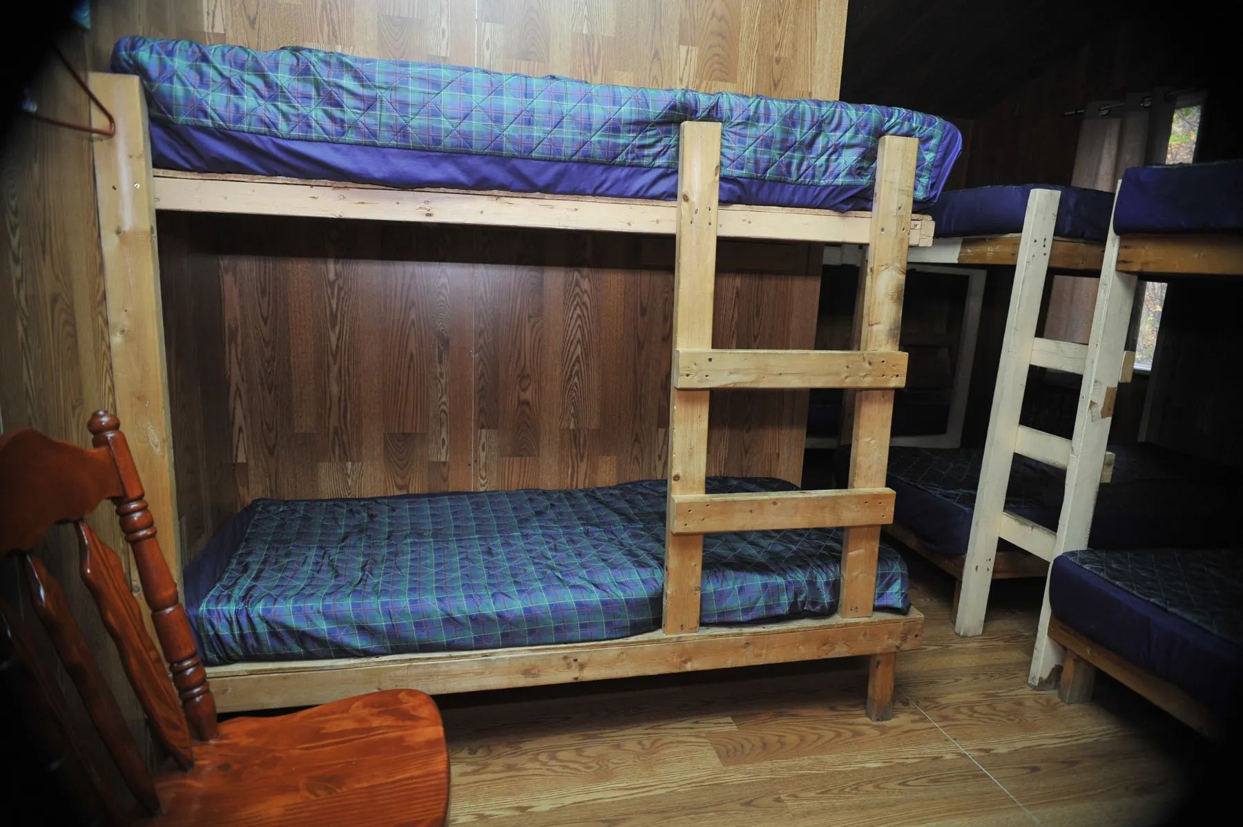 The bedroom in Le Vétéran cabin is equipped with wooden bunk beds.