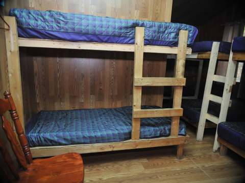 The bedroom in Le Vétéran cabin is equipped with wooden bunk beds.