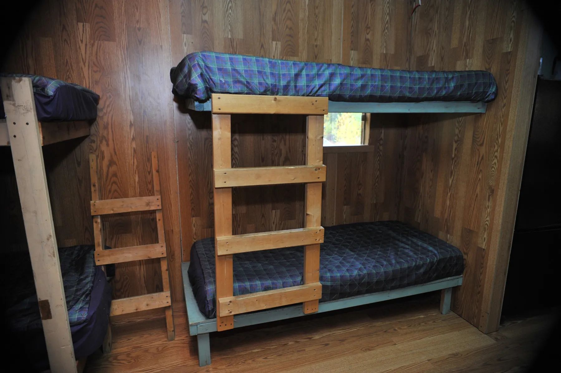 The bedroom is equipped with wooden bunk beds with plaid patterned bedspreads.