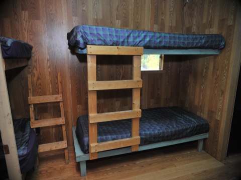 The bedroom is equipped with wooden bunk beds with plaid patterned bedspreads.