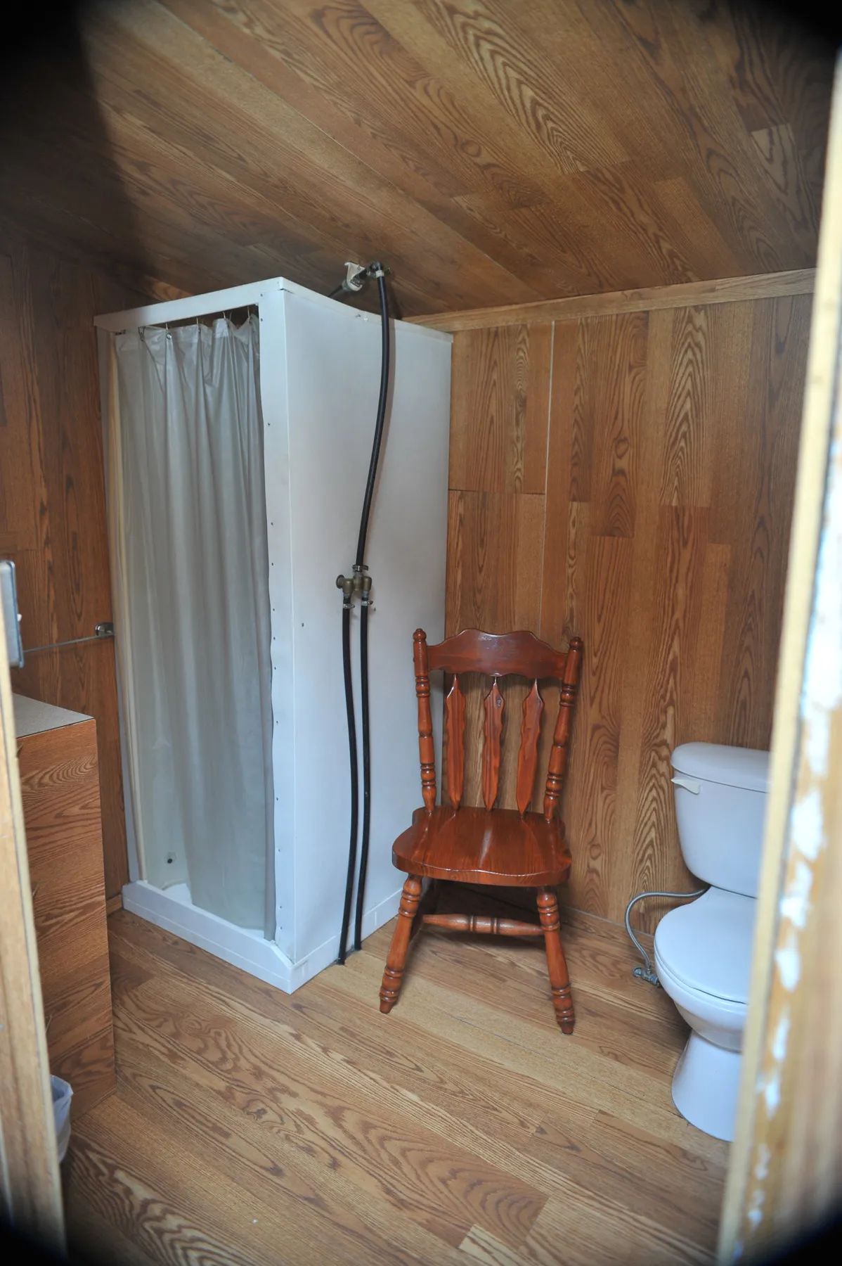 La salle de bain du chalet comprend une douche, une toilette et un revêtement mural en bois.