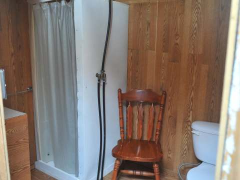 La salle de bain du chalet comprend une douche, une toilette et un revêtement mural en bois.