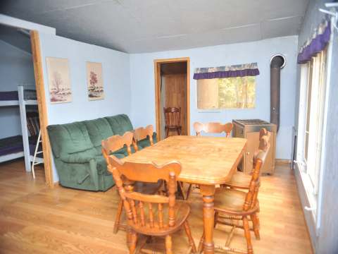 L'intérieur du chalet Le Rustique comprend une table à manger, un coin salon et des lits superposés.