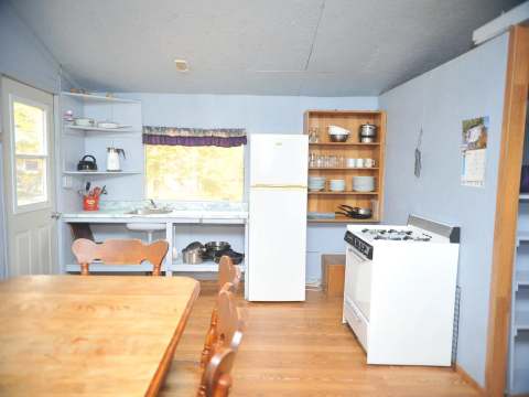La cuisine fonctionnelle du chalet Le Rustique comprend une cuisinière, un réfrigérateur et une table.